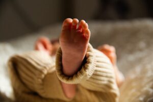 Foot of unrecognizable newborn baby lying in crib