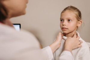 Doctor Checking Girl's Throat Tonsils by Touching Her Neck