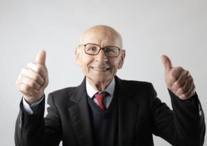 Positive senior man in eyeglasses showing thumbs up and looking at camera